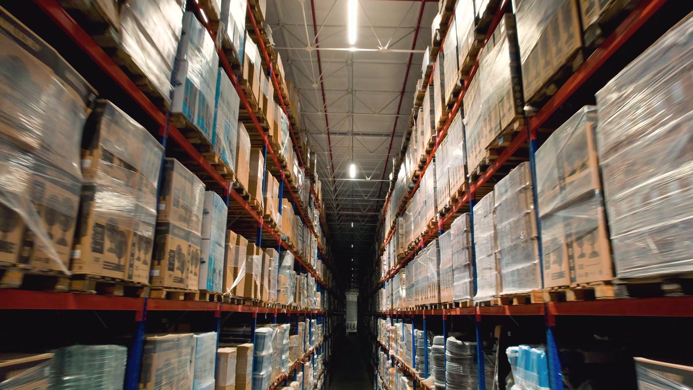 Corredor entre estantes altas de um centro de distribuição iluminado